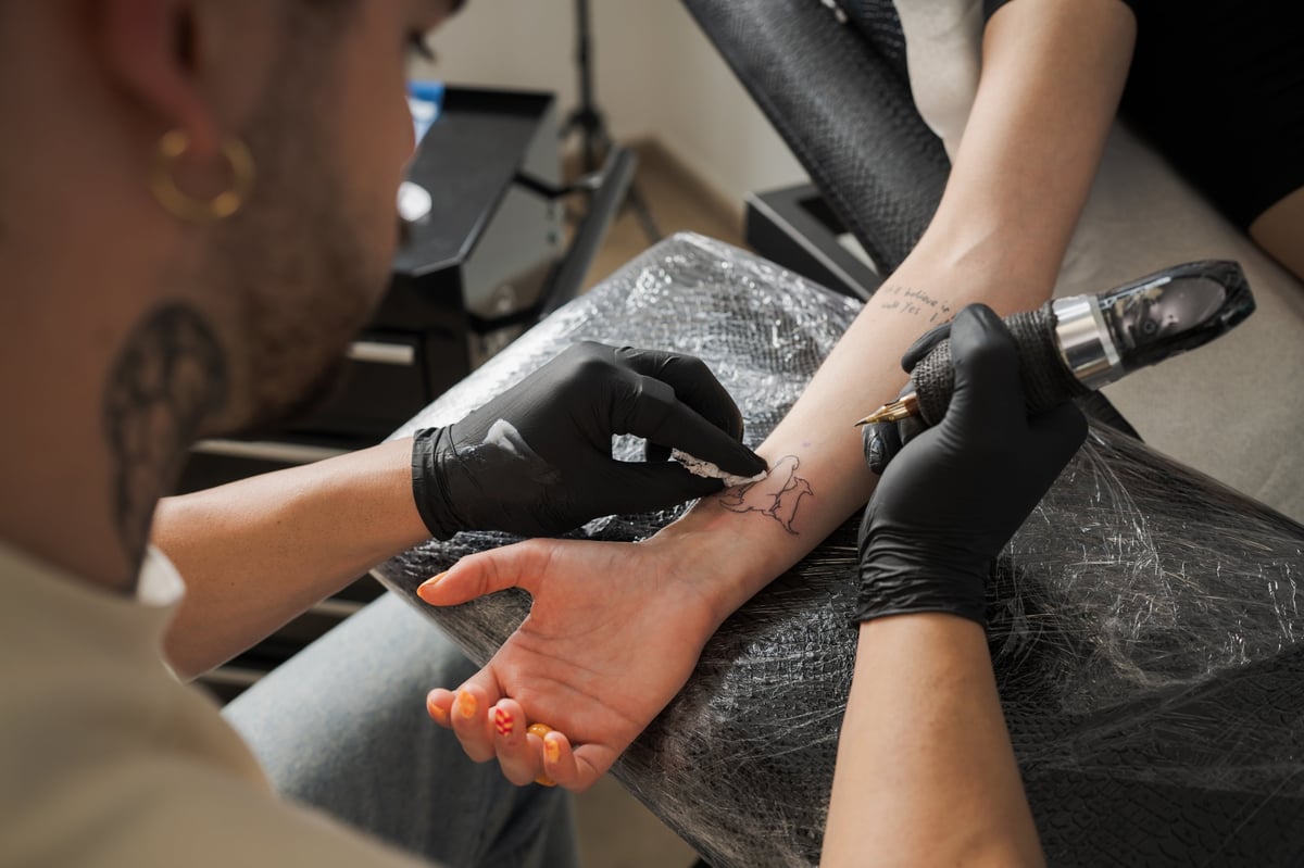 Tattoo artist carefully drawing design on client