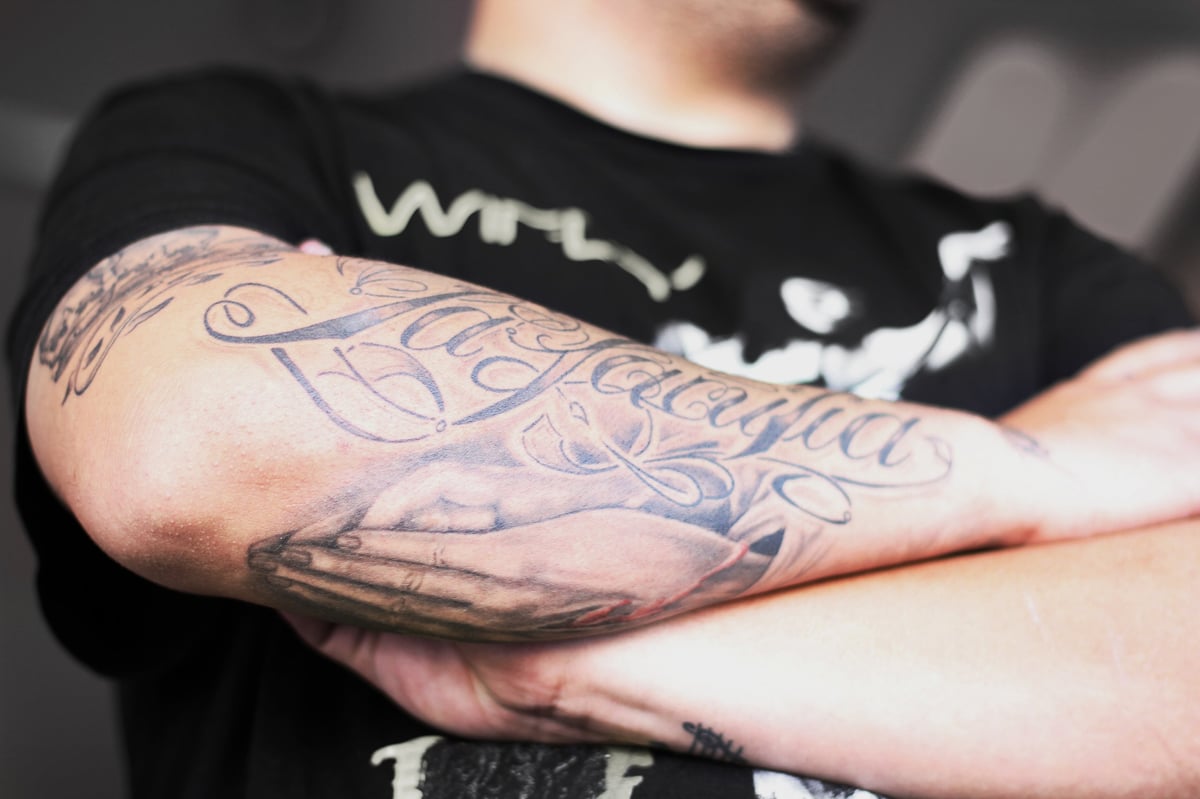 Closeup shot of a man crossing his tattooed arms